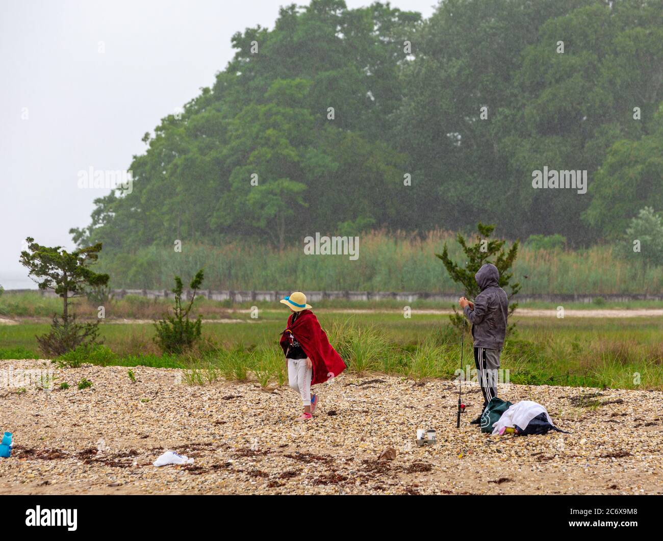 Un couple sur une plage rocheuse de Shelter Island pêche dans la pluie Banque D'Images