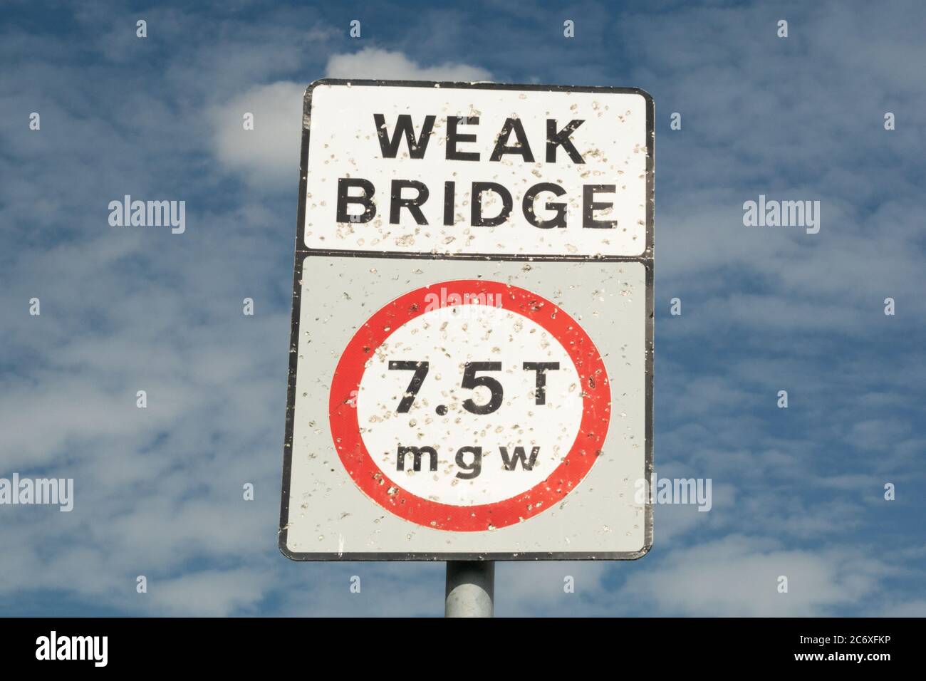 Un panneau indiquant « PONT FAIBLE 7,5t mgw » qui a été tiré à plusieurs reprises avec un pistolet à air. Ciel bleu avec nuages. Angleterre, Royaume-Uni Banque D'Images