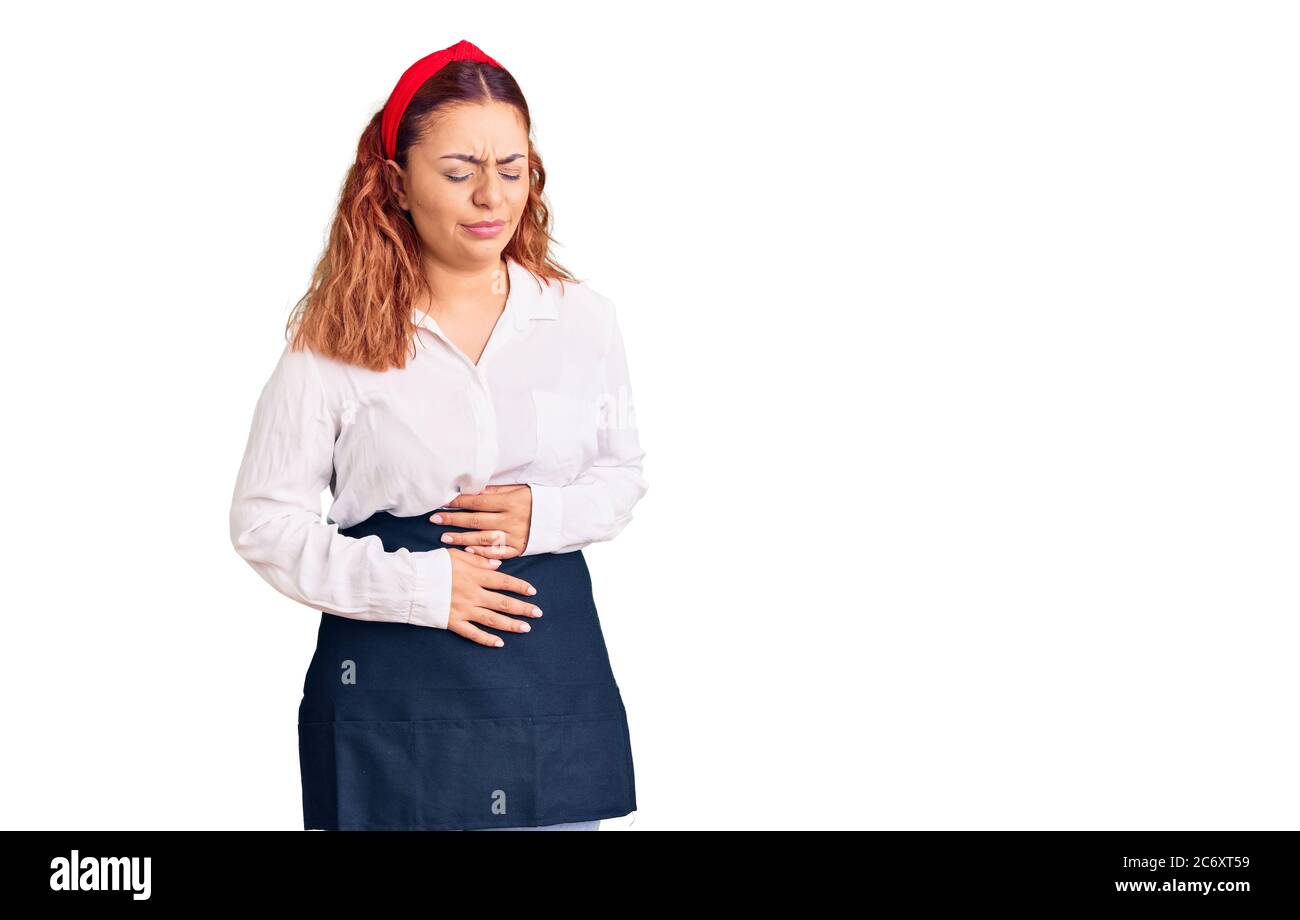 Jeune femme latine portant un tablier de serveuse avec main sur l'estomac parce que l'indigestion, la maladie douloureuse se sentir mal. Ache concept. Banque D'Images