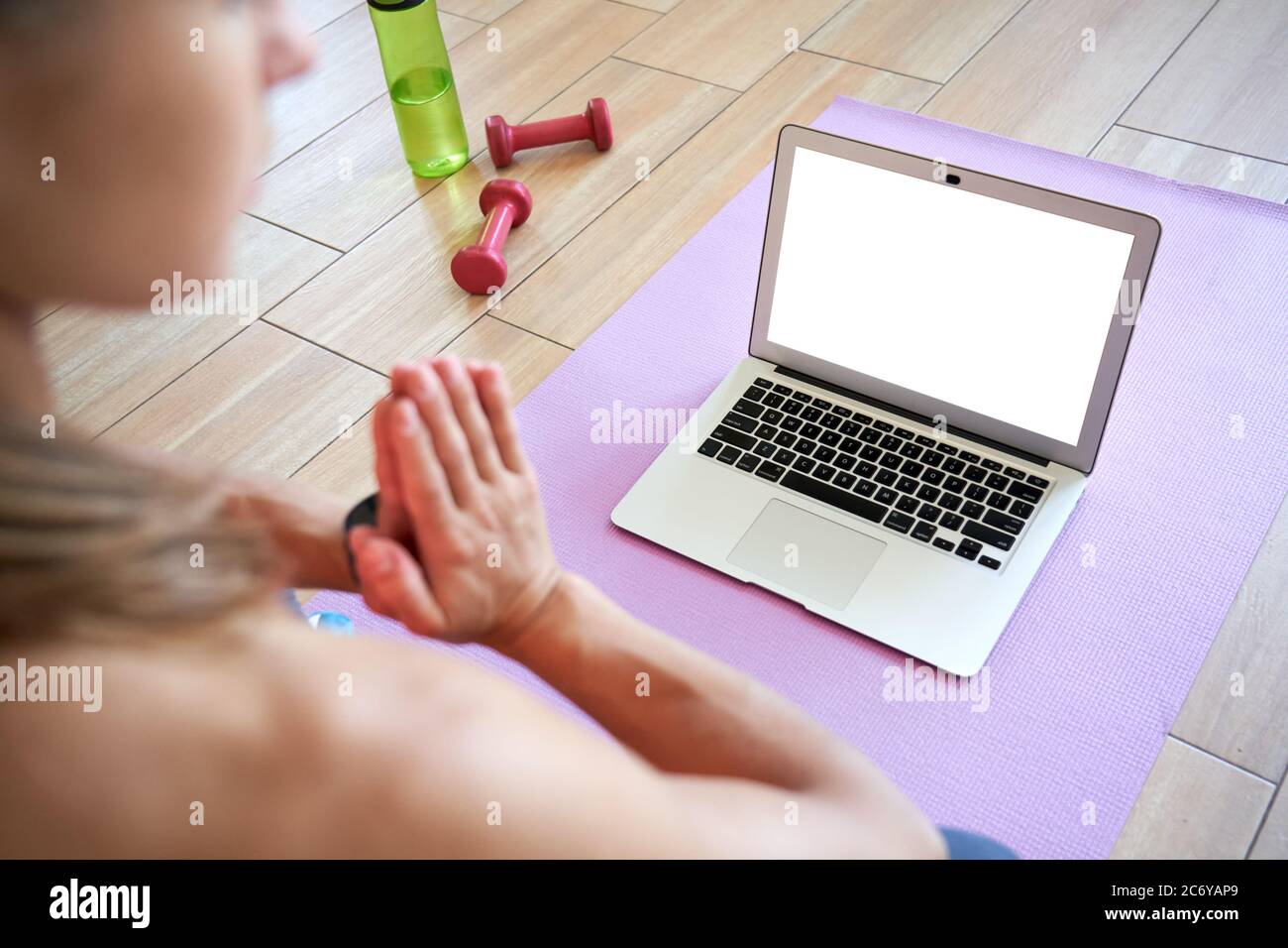 Vue sur l'épaule de la femme méditer regarder le yoga en ligne sur l'écran maquette d'ordinateur portable. Banque D'Images