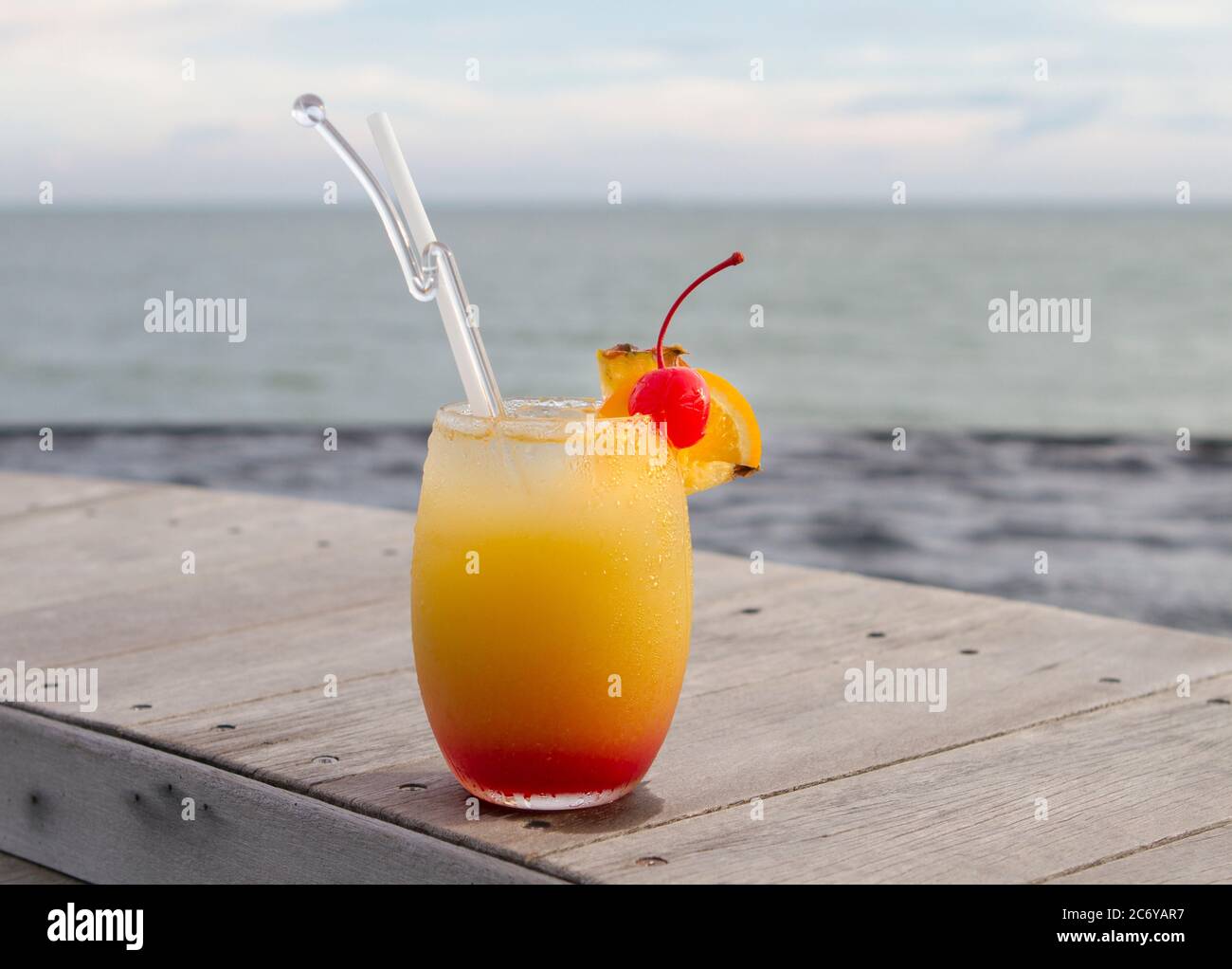 Verre de punch de fruits sur le dessus en bois avec vue sur l'océan Photo  Stock - Alamy
