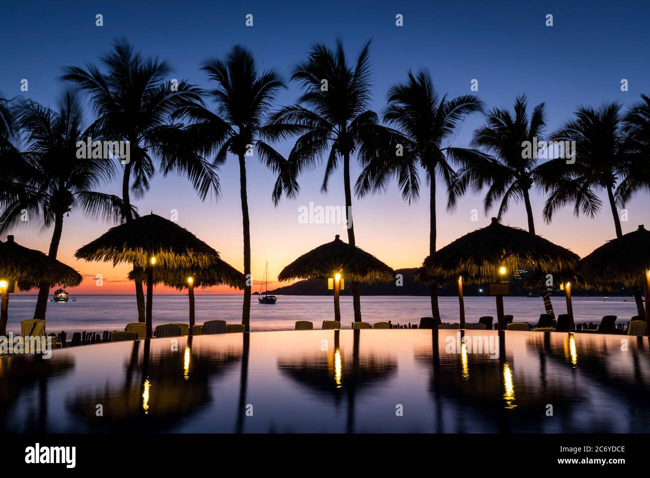 Piscine à débordement de l'hôtel Playa Mexicana au crépuscule à Zihuatanejo, Guerrero, Mexique. Banque D'Images