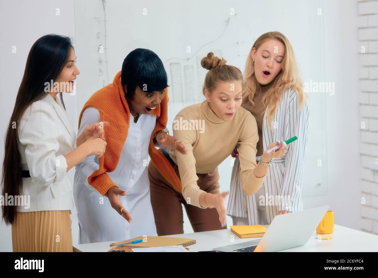 Les jeunes femmes d'affaires surprendra vêtues de vêtements décontractés restent sous le choc après les nouvelles de leur projet gagnant dans les affaires, partager le succès avec chaque othe Banque D'Images