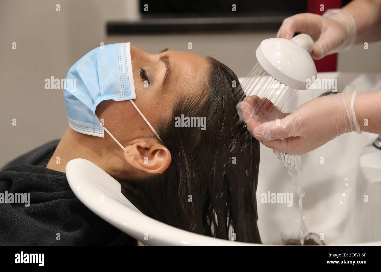 Shireen Inglis a lavé ses cheveux tout en portant un masque facial à la Fringe lunatique de Glasgow, car ils démontrent certains des changements mis en place pour aider à protéger contre le coronavirus. Les coiffeurs de toute l'Écosse se préparent à rouvrir aux clients mercredi, car les mesures de verrouillage sont assouplies. Banque D'Images
