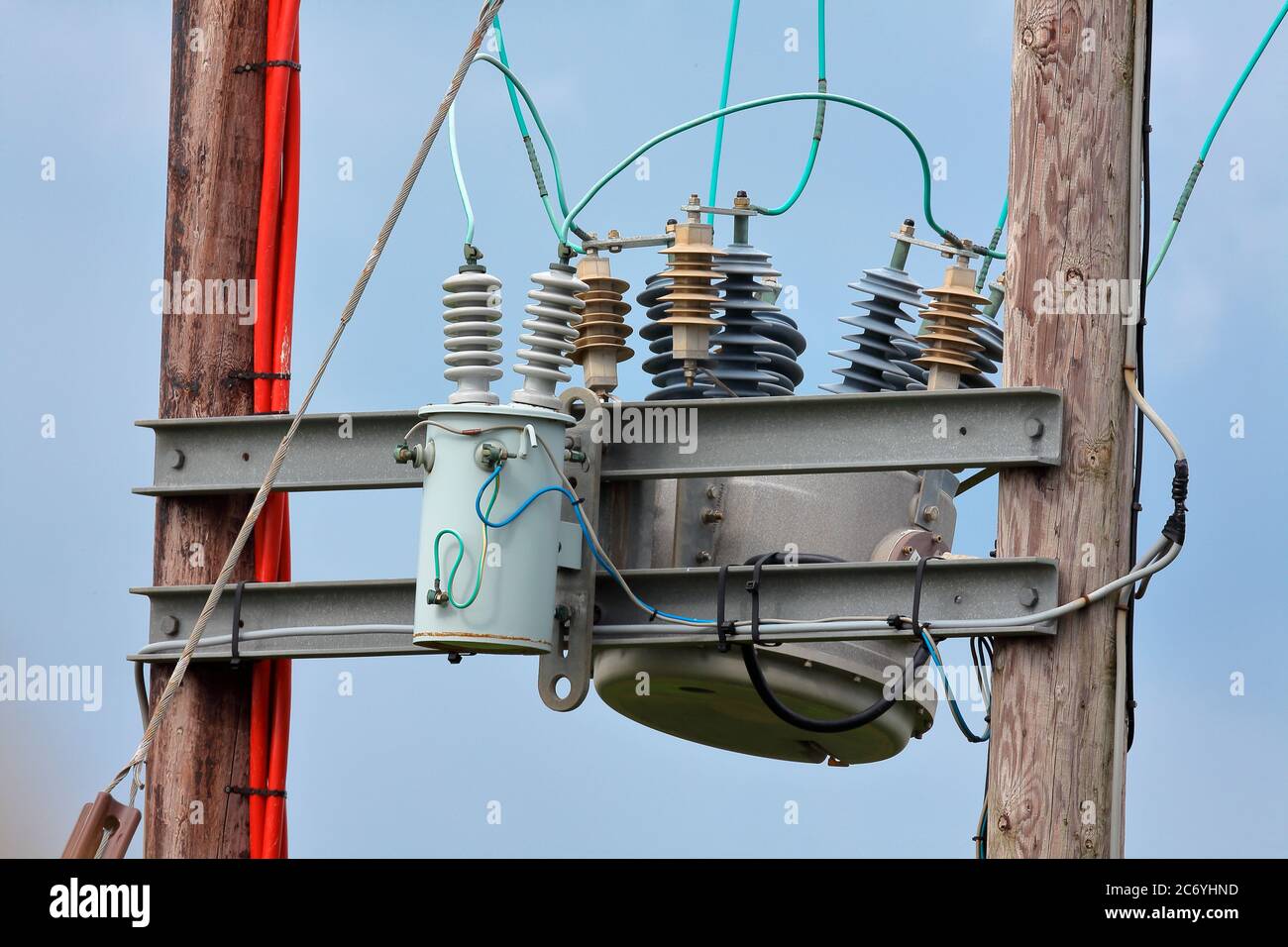 Un transformateur haute tension réduisant la tension de la ligne aérienne pour fournir des propriétés domestiques dans un endroit rural avec les travaux électriques élevés. Banque D'Images