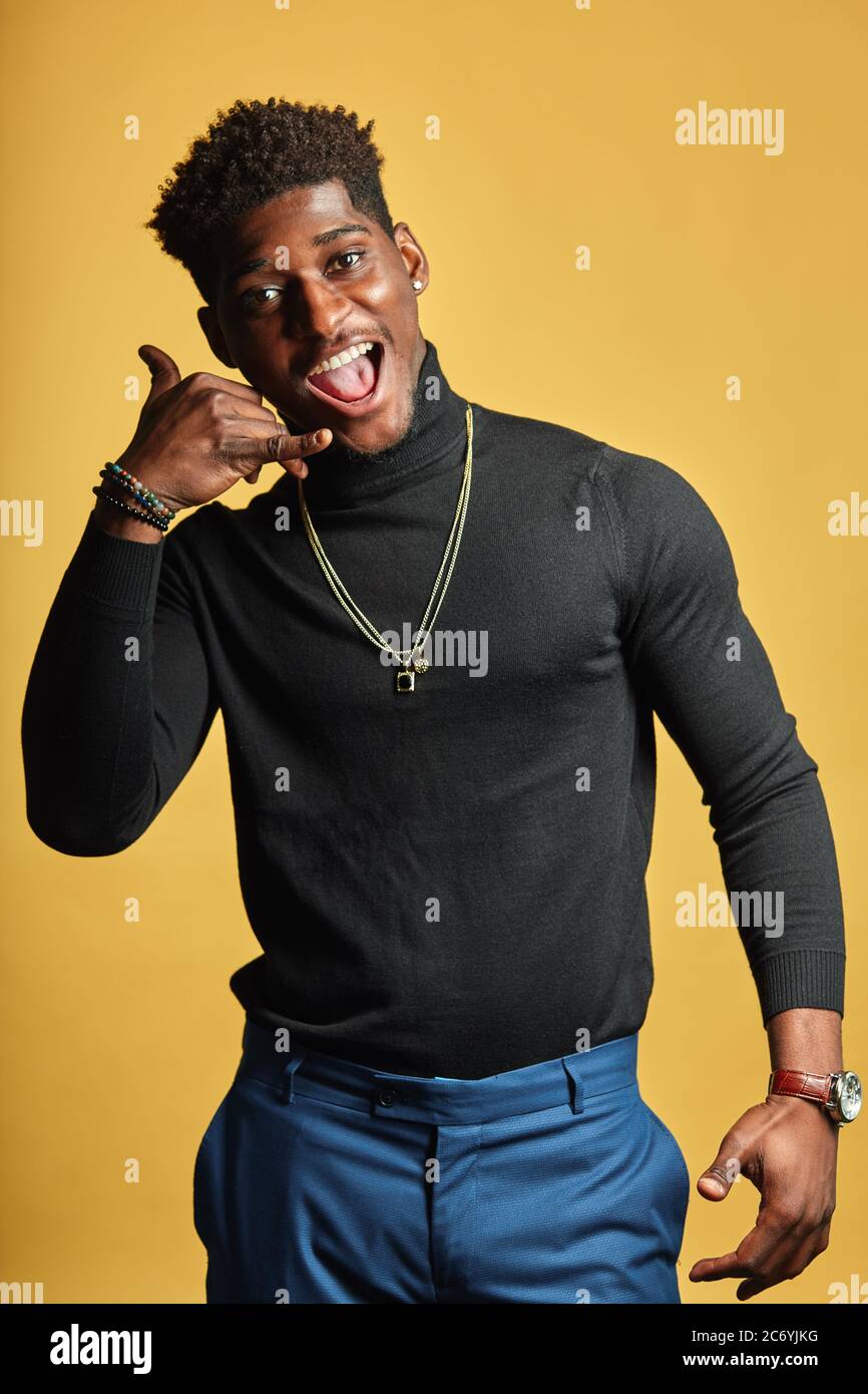 Bebe Appelez Moi Un Beau Homme Africain Tient Sa Main Comme Telephone Pres De L Oreille Garde La Bouche Ouverte Se Rejouit De La Connaissance Avec Une Nouvelle Fille Isolee Sur Yel Photo Stock