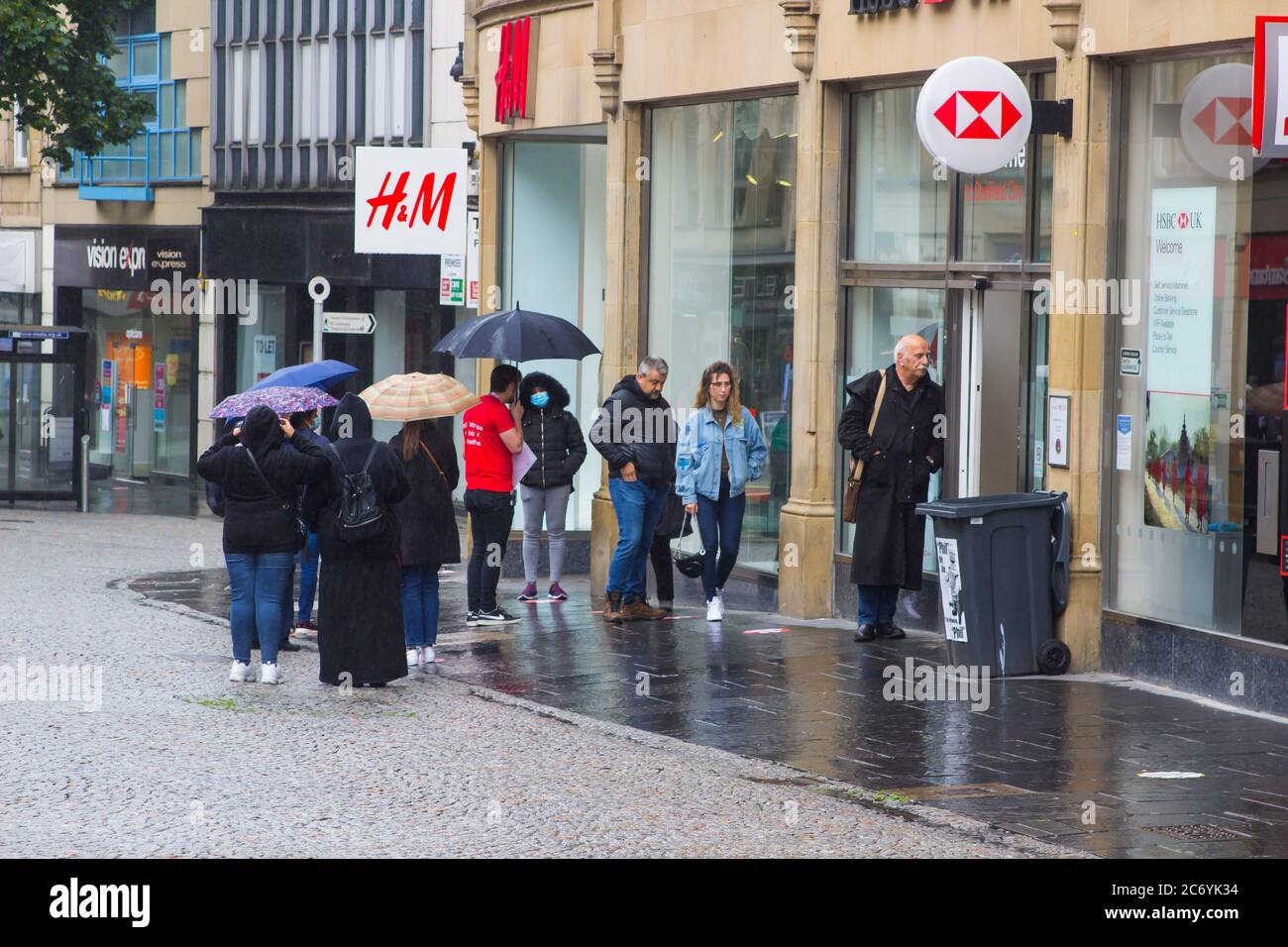8 juillet 2020 les clients maintiennent leurs distances sociales en faisant la queue sous la pluie à l'extérieur de la succursale de la HSBC Bank à Fargate Sheffield, en Angleterre Banque D'Images