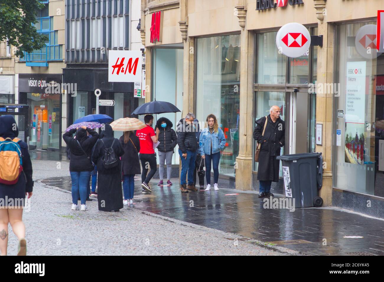 8 juillet 2020 les clients maintiennent leurs distances sociales en faisant la queue sous la pluie à l'extérieur de la succursale de la HSBC Bank à Fargate Sheffield, en Angleterre Banque D'Images