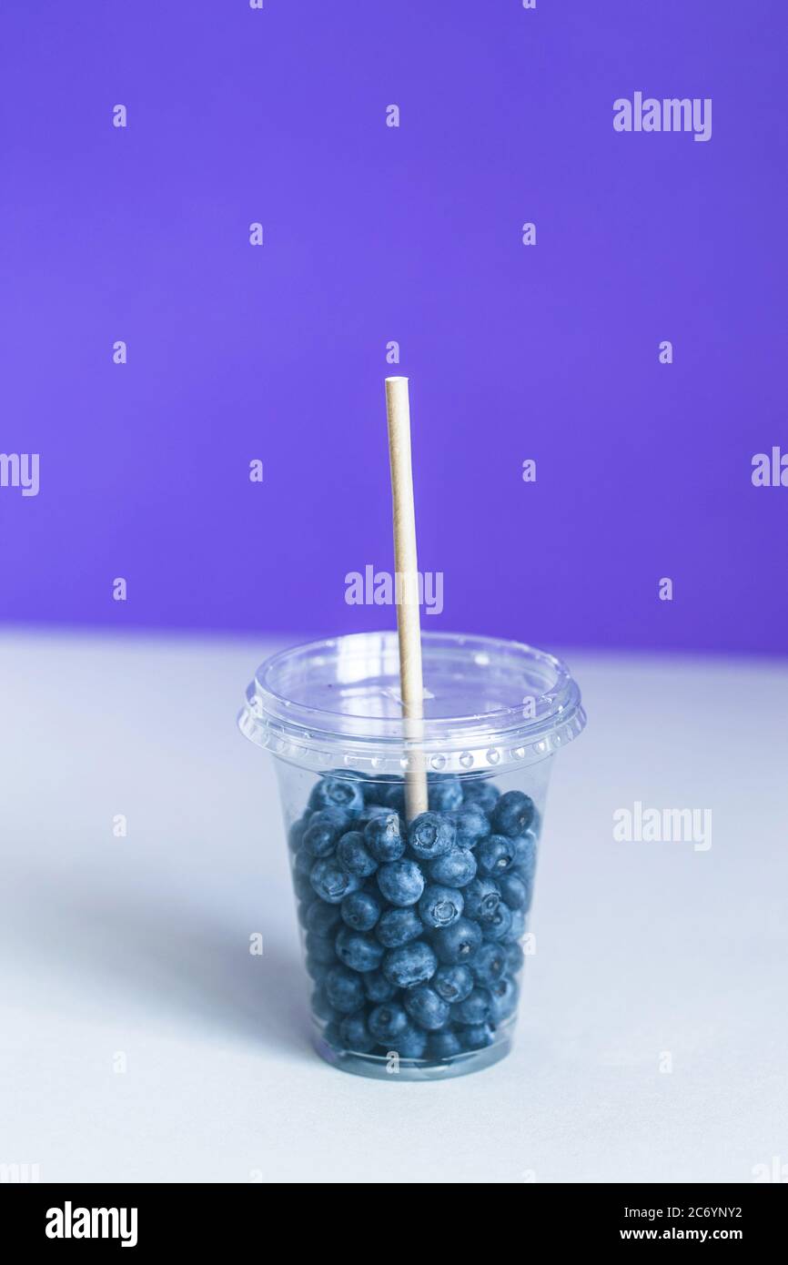 Bleuet dans la tasse en plastique smoothie avec une paille en papier Banque D'Images