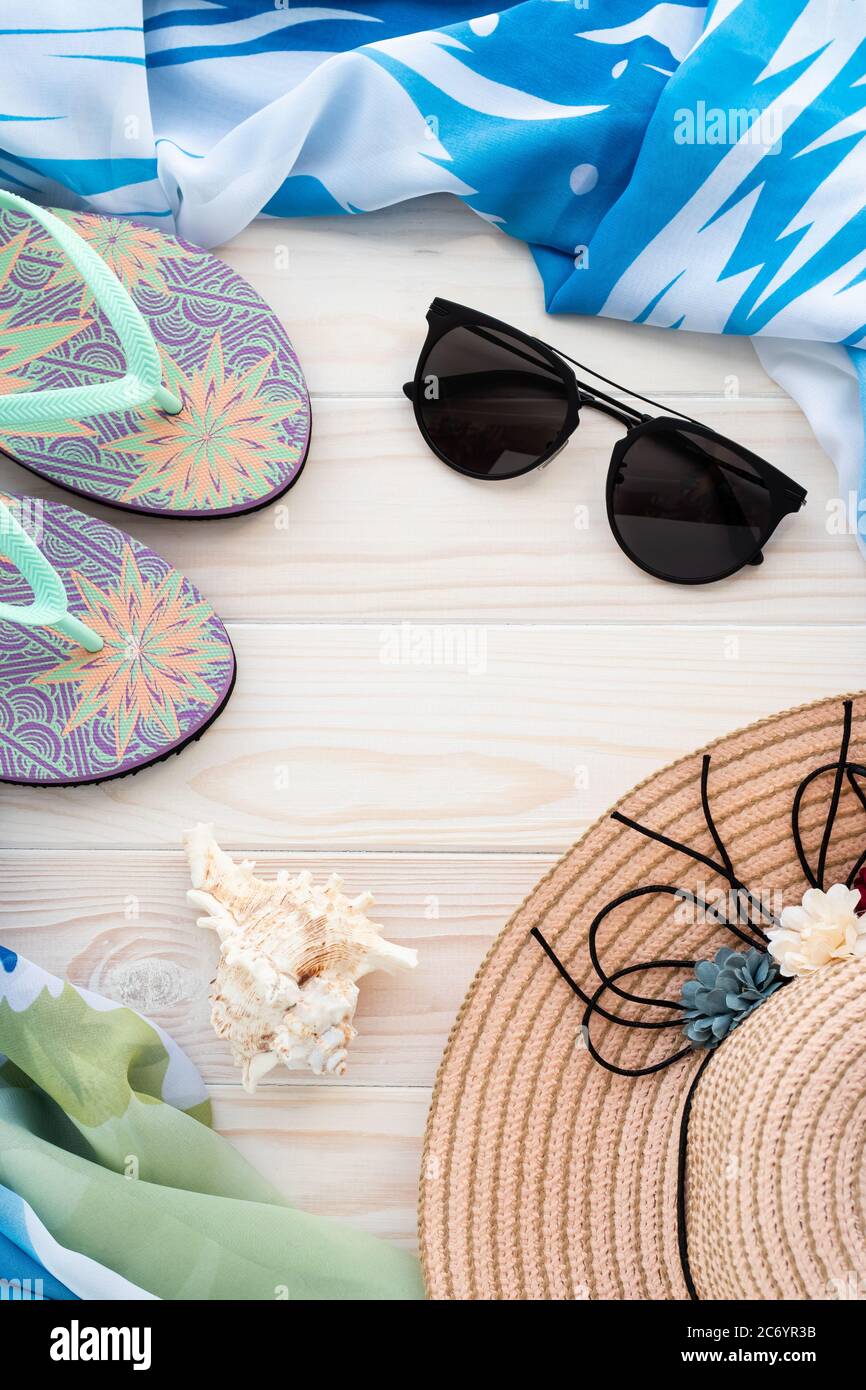 Vacances d'été avec seashell, tongs sandales, lunettes de soleil, pareo et chapeau de paille sur des planches de bois. Concept de vacances à la plage et à la mer. Mur Banque D'Images