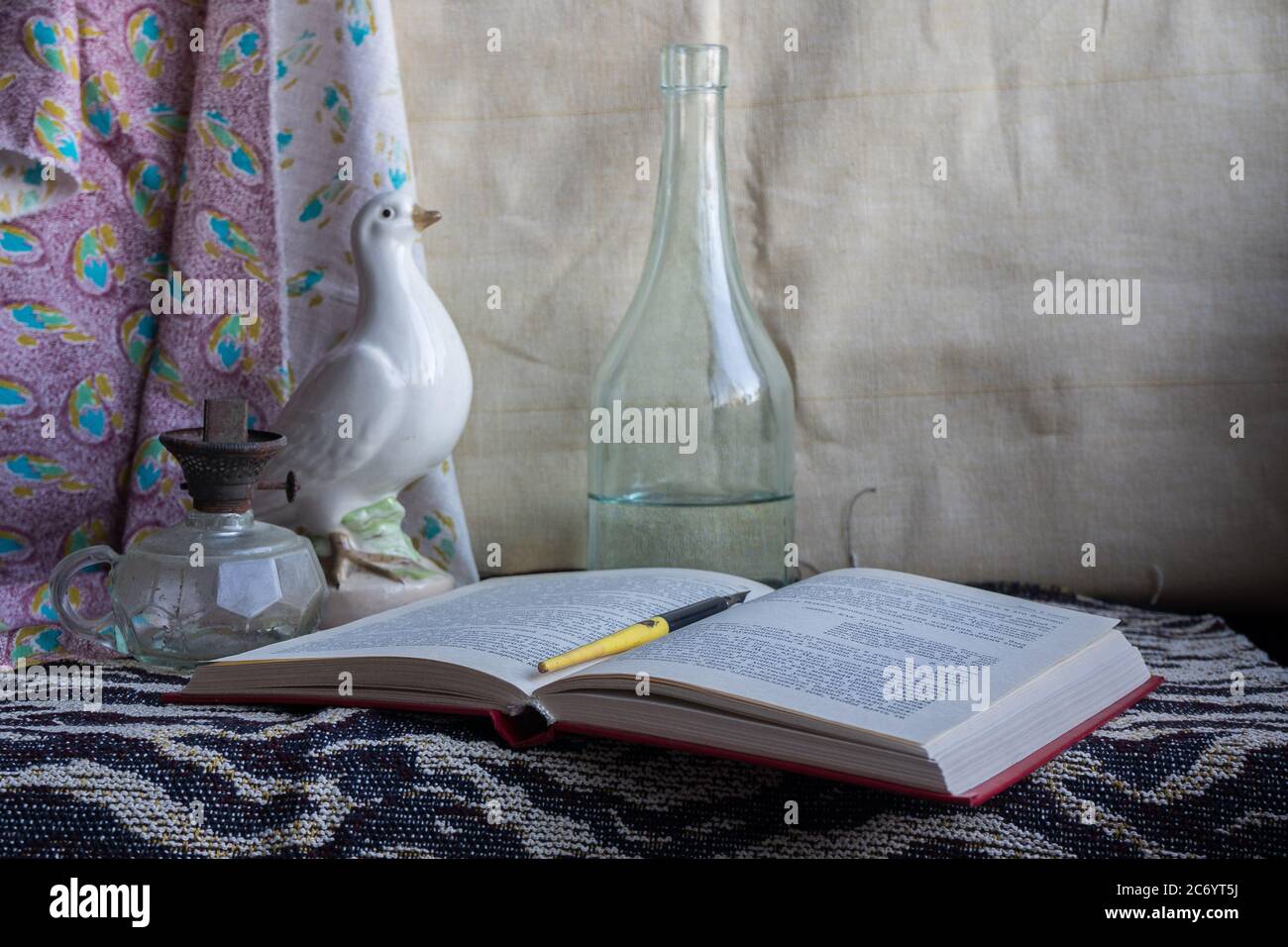 La vie est encore plus longue avec un livre, une plume, une colombe en porcelaine, une lampe à alcool et une bouteille en verre. Banque D'Images
