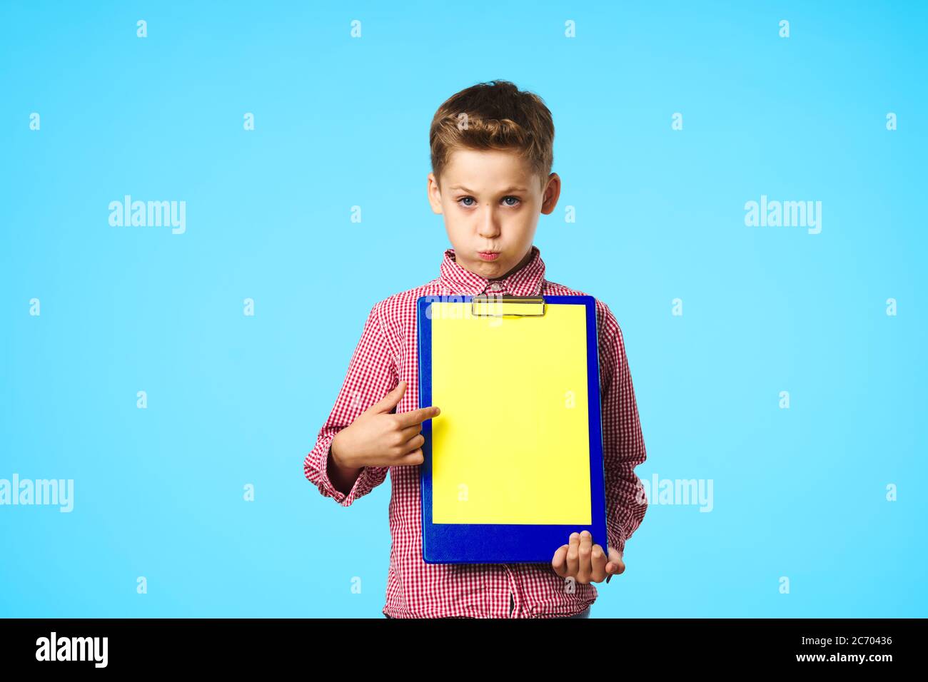 L'enfant a boudé ses lèvres et tient dans sa main un dossier Banque D'Images