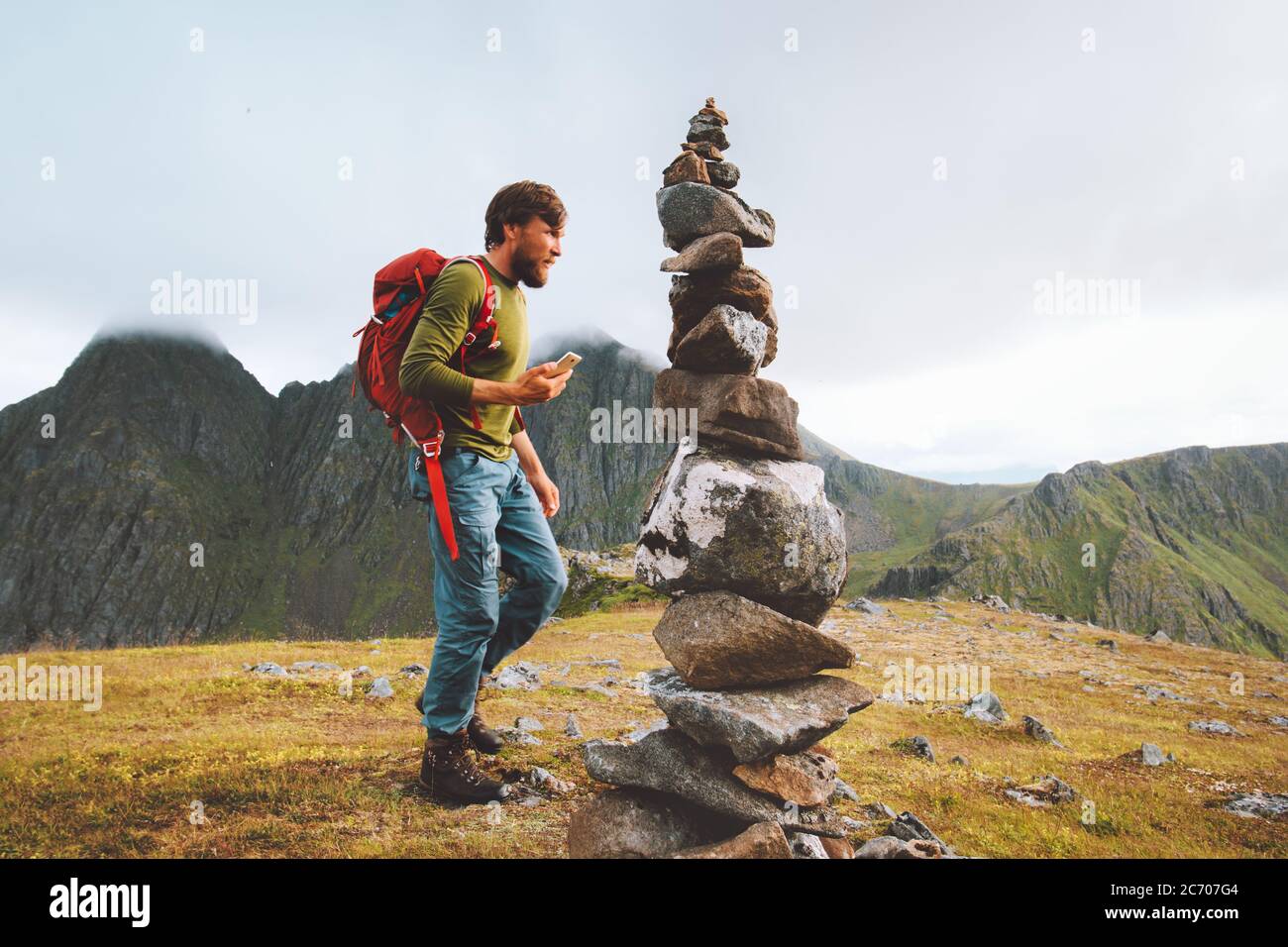Homme randonnée avec sac à dos utilisation de smartphone pour la navigation rock cairn marquage itinéraire sur sommet de montagne Voyage sain style de vie concept active aventure Banque D'Images