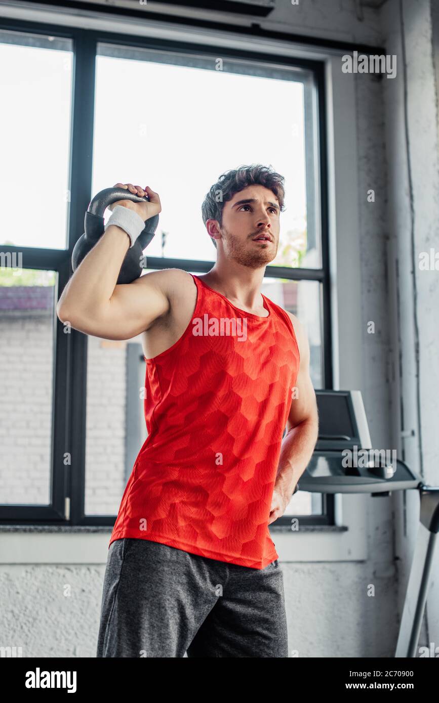 sportif, homme s'ébatant avec une haltère tout en se tenant main sur la hanche Banque D'Images