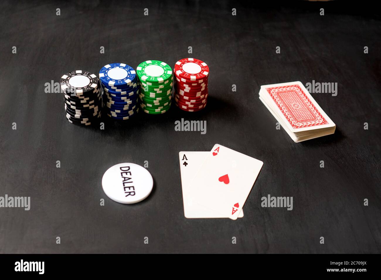 Deux as de cartes, puce de revendeur et jetons pour le jeu de poker. Arrière-plan noir, vue de dessus. Banque D'Images