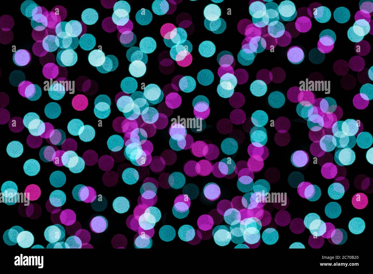 Lumières floues sur fond noir. Bokeh rose et turquoise, concept festif. Banque D'Images