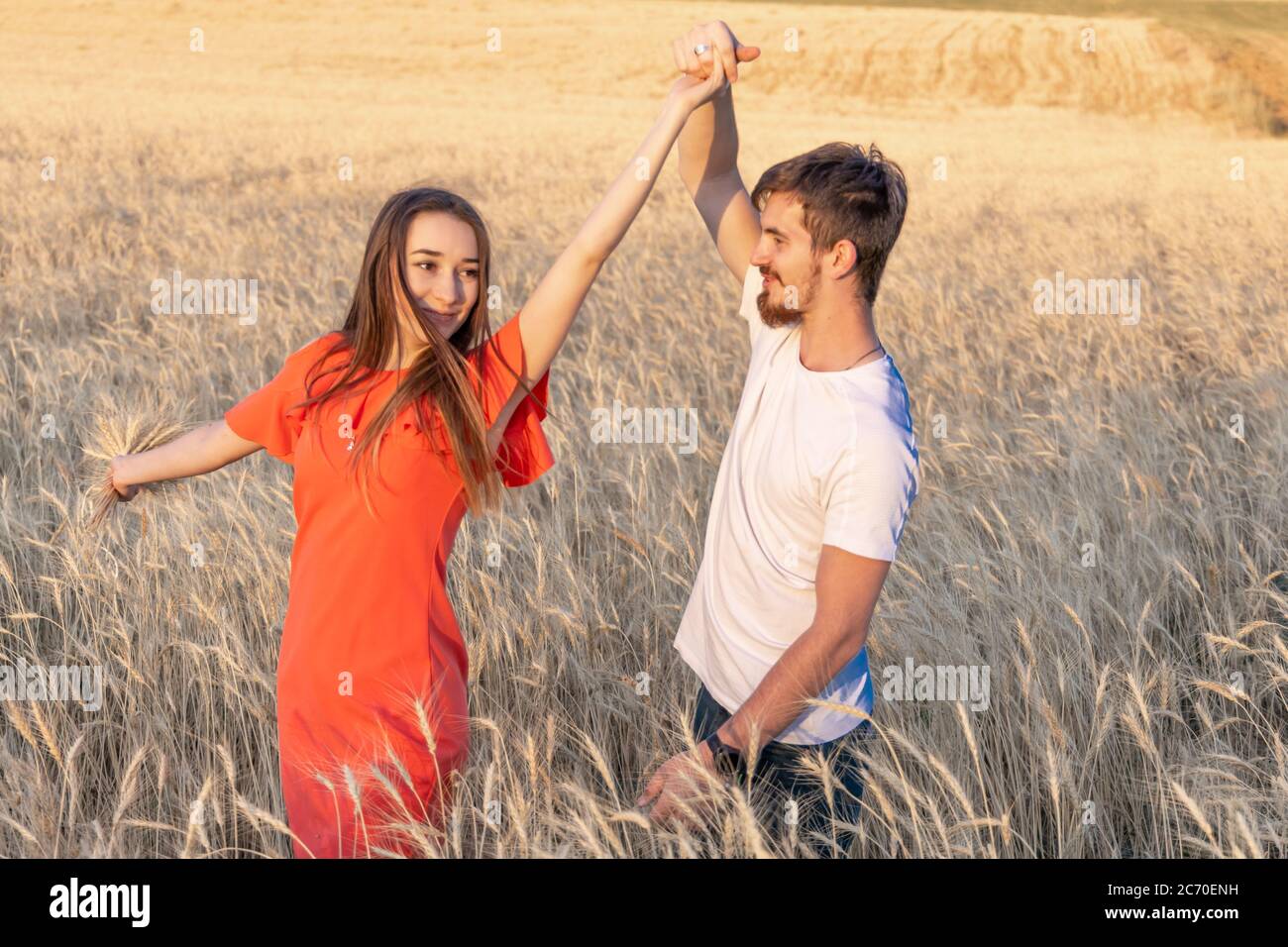 Jeune couple danse champ de blé. Homme prenant la main d'une femme un tourbillon de sa petite amie Banque D'Images