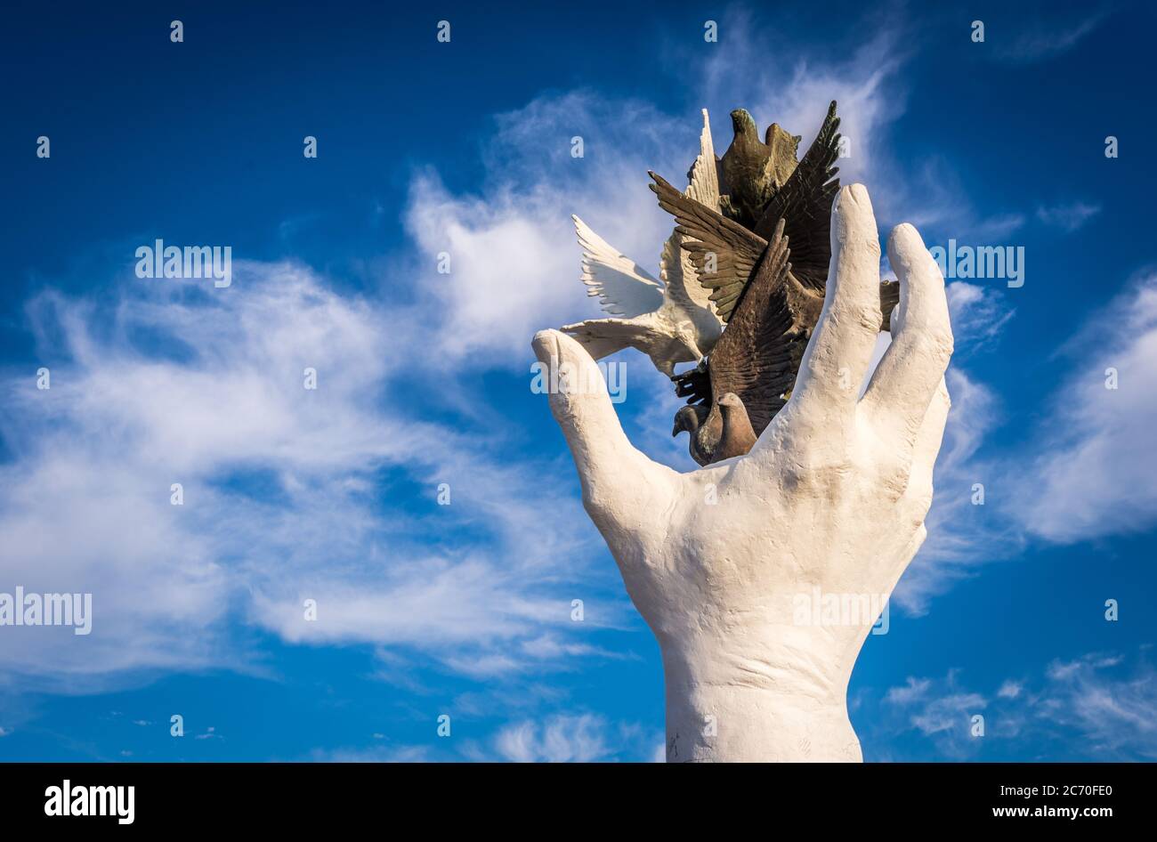 Statue d'une main qui libère des oiseaux de différentes couleurs, symbolisant la liberté, la diversité et la paix Banque D'Images