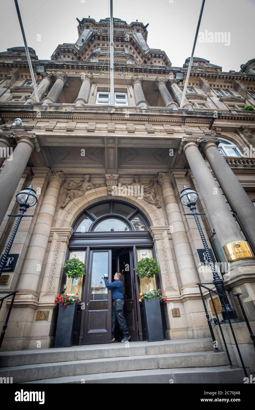 Un membre de l'équipe de maintenance du Balmoral, à Édimbourg, nettoie la porte d'entrée alors que les hôtels commencent à préparer leur réouverture le mois prochain, alors que l'Écosse se prépare à lever d'autres restrictions de verrouillage du coronavirus. Banque D'Images