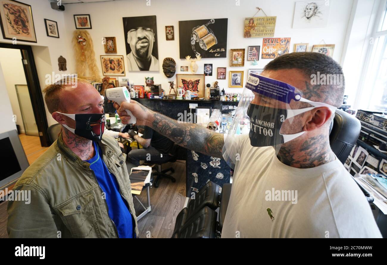 DaN Ridgewell, 41 ans, est l'artiste du tatouage qui prend la température d'un client au magasin de tatouage Ax & Anchor de North Shields, North Tyneside, alors qu'il rouvre ses portes aux clients suite à l'assouplissement des restrictions de verrouillage en Angleterre. Banque D'Images