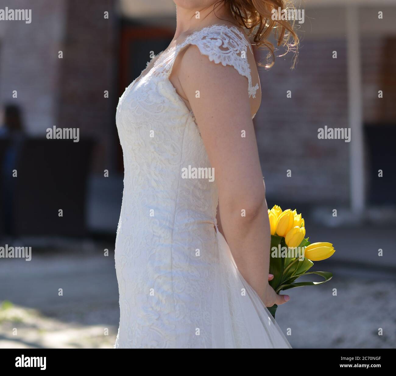 photographies urbaines d'une mariée portant une robe blanche et portant un bouquet de tulipes jaunes entre ses mains Banque D'Images