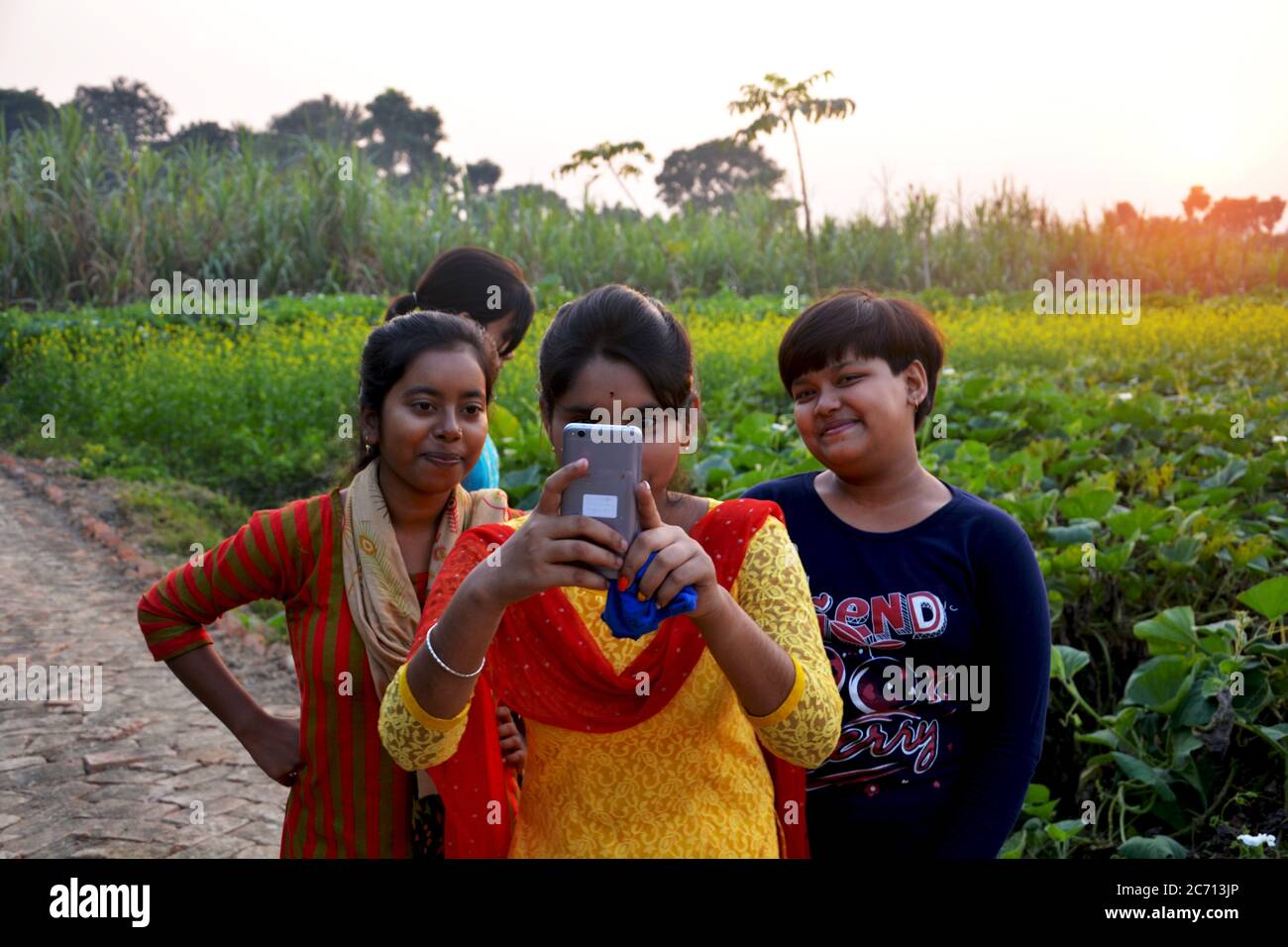 Une adolescente indienne prenant des photos par téléphone mobil et des amis regardant, sélective focalisation Banque D'Images