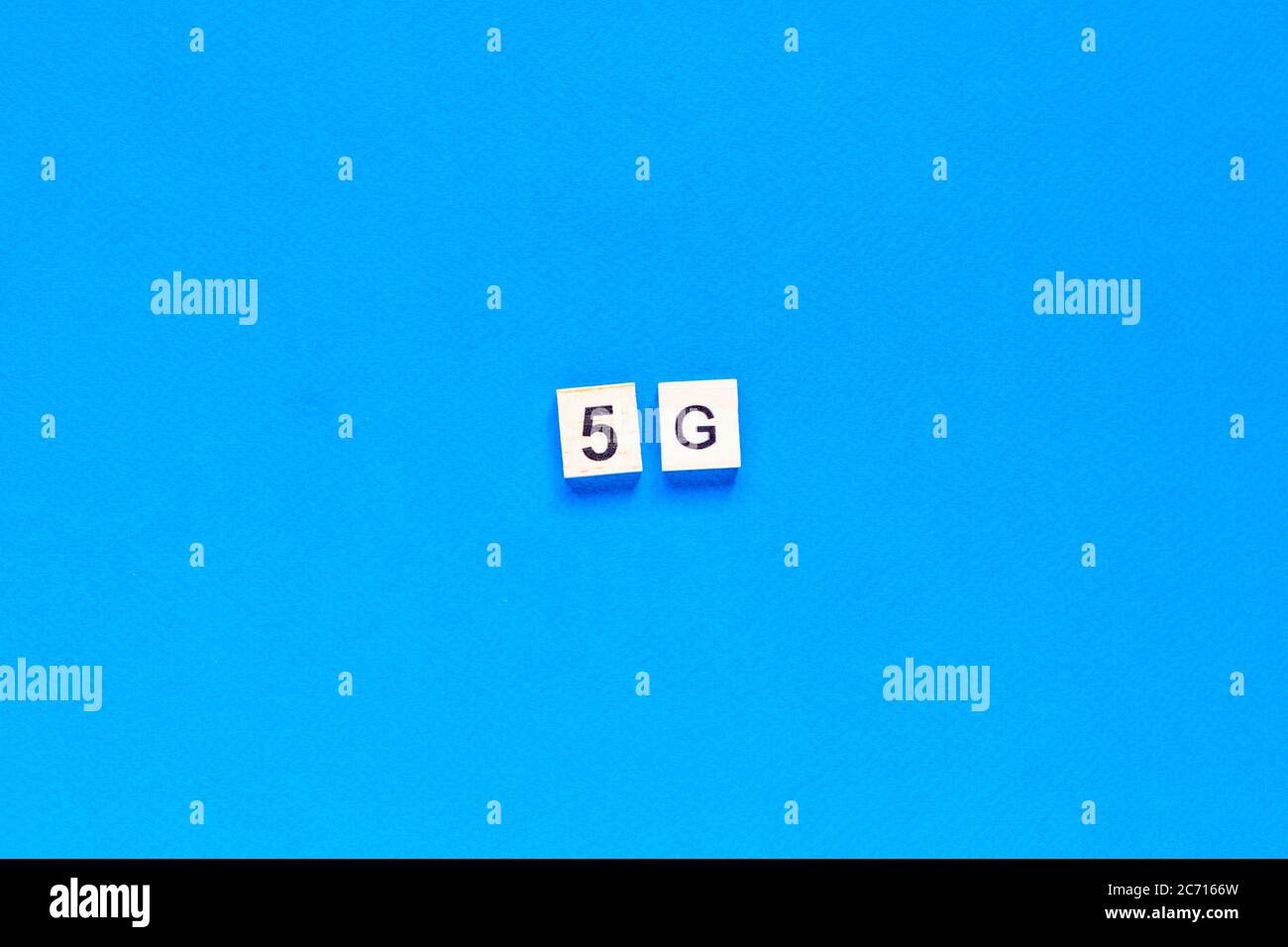 5 G. Five G's, écrit en lettres de bois sur fond bleu. Mise en page à plat. Réseau sans fil. Nouvelle technologie. Vue du dessus. Banque D'Images