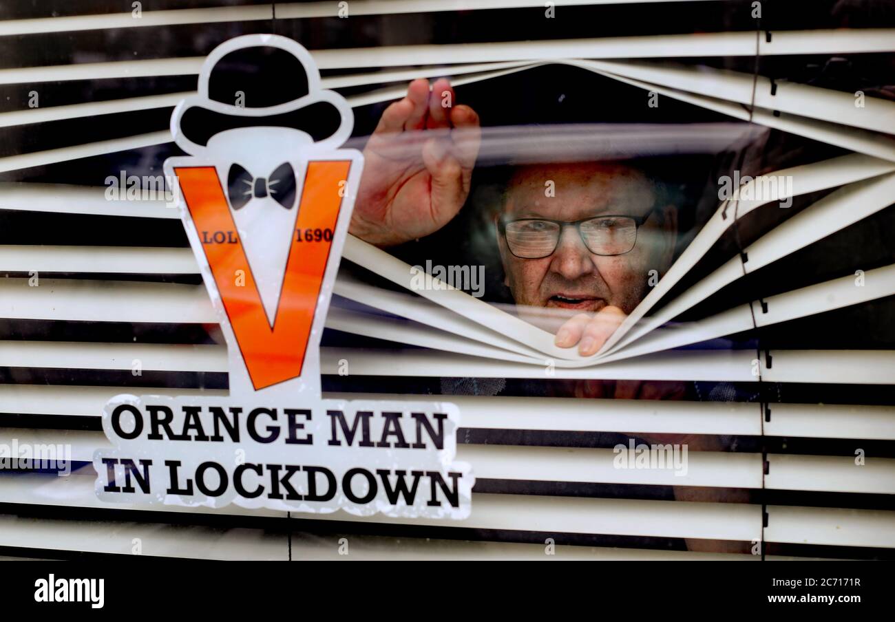 Orange Man, Randy Davidson, qui isole à la maison, pose avec un autocollant dans sa fenêtre pour célébrer le 12 juillet, les défilés traditionnels à grande échelle ayant été annulés cette année en raison de la pandémie. Banque D'Images