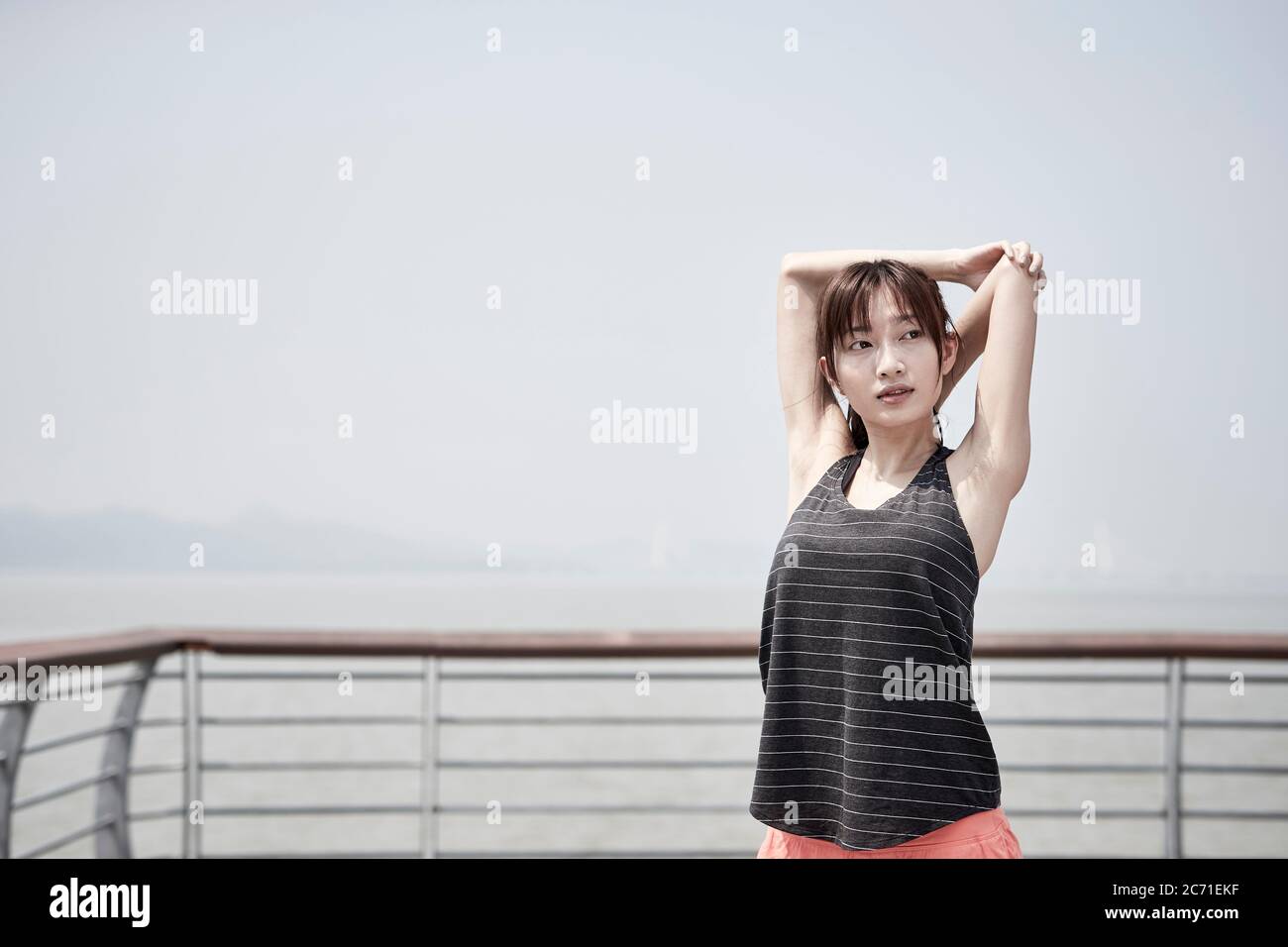 jeune femme adulte asiatique qui s'étend les bras à l'extérieur au bord de la mer Banque D'Images