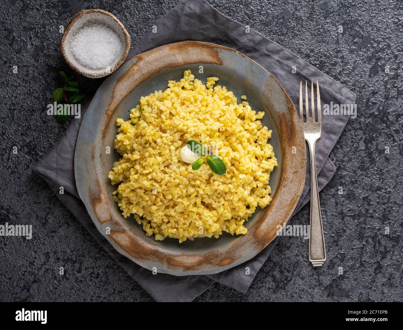 Boulgour blé. Céréales bouillies bulghour dans une assiette sur une table en pierre gris foncé. Nourriture végétarienne saine, vue de dessus Banque D'Images