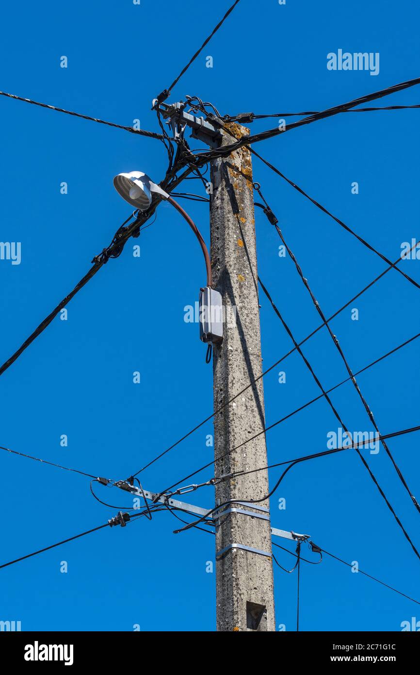 Vieux téléphone, câblage électrique et lumière de rue sur le mât télégraphique dans la France rurale. Banque D'Images