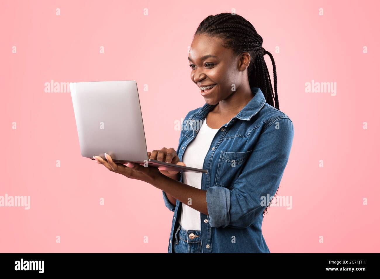 Gaie Black Woman utilisant un ordinateur portable debout sur fond rose Banque D'Images