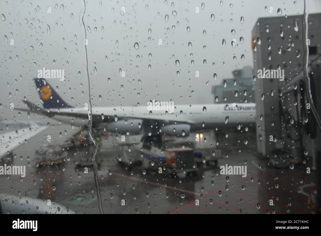 Airbus A340 de Lufthansa étant embarqué à l'aéroport Frankfirt am main, vu depuis un A320 à la porte suivante sous une forte pluie. Banque D'Images