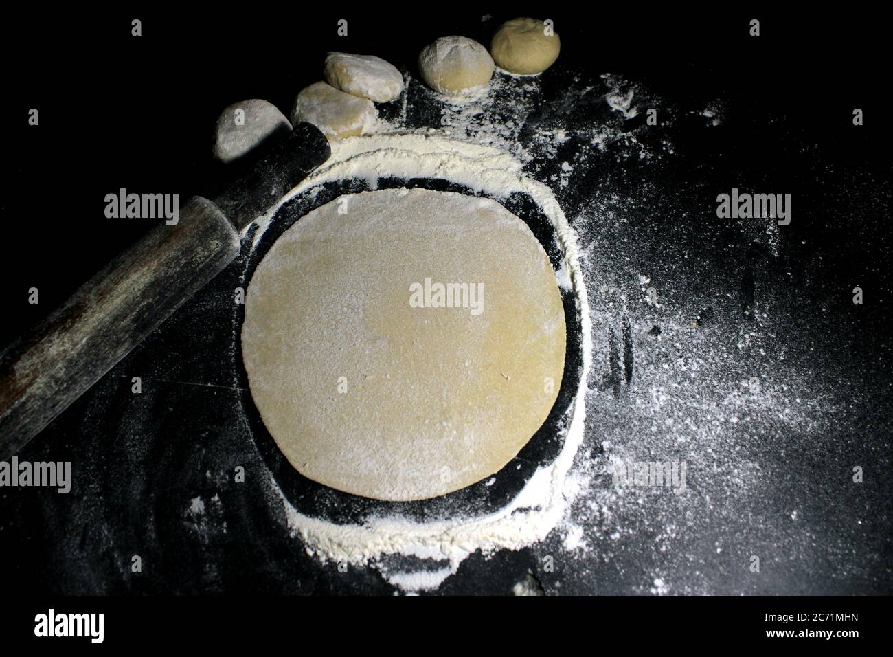 Pâte à levure avec farine de blé sur fond noir. Boule de pain non cuite pour la fabrication de Roti ou Chapati (pain plat indien). Banque D'Images