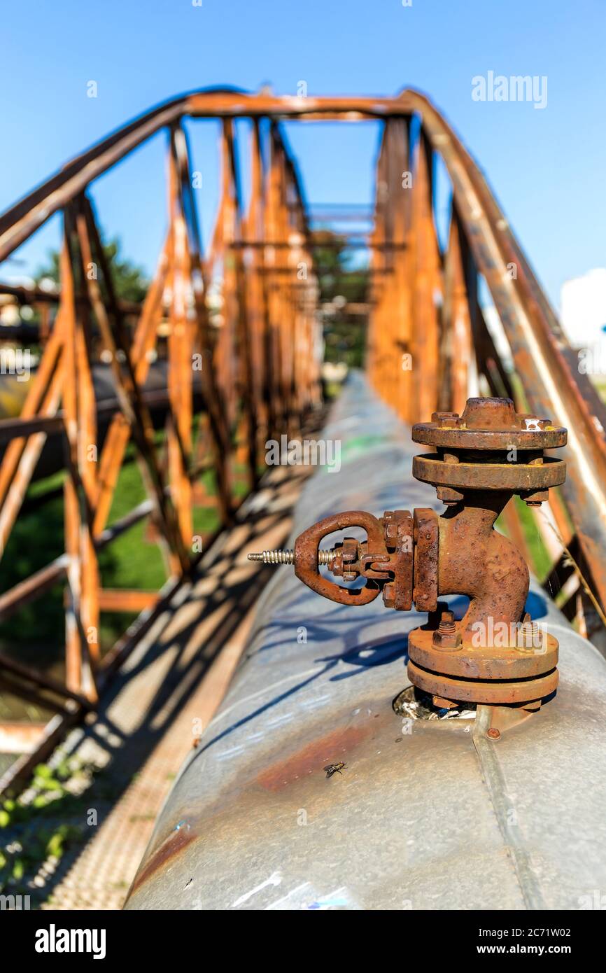 Vieux pont en fer rouillé au-dessus de la rivière avec un pipeline de vapeur. Alimentation en chaleur. Équipement industriel. Vue détaillée d'une vanne de canalisation de vapeur. Banque D'Images