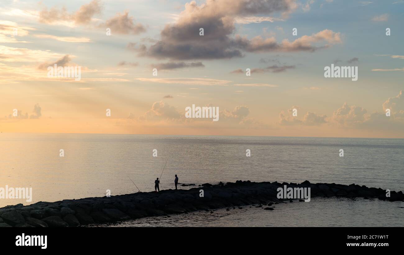 Silhouette de pêcheur décontractée sur la jetée à l'heure bleue Banque D'Images