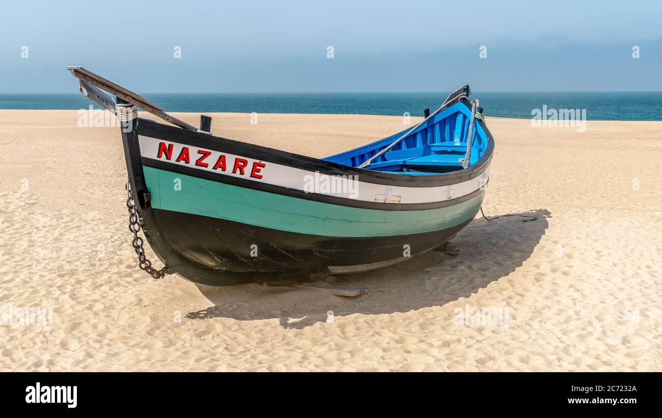 Nazaré, Portugal - avril 2018 : ancien bateau de pêche traditionnel coloré en bois sur la plage du village de pêcheurs de Nazaré.la haute falaise de Nazaré Sitio A. Banque D'Images