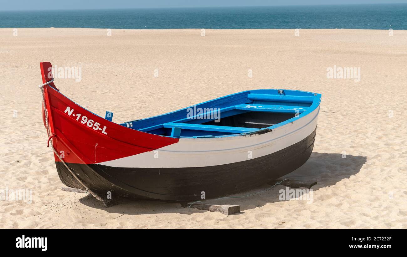 Nazaré, Portugal - avril 2018 : ancien bateau de pêche traditionnel coloré en bois sur la plage du village de pêcheurs de Nazaré.la haute falaise de Nazaré Sitio A. Banque D'Images