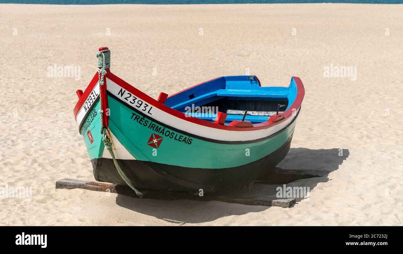 Nazaré, Portugal - avril 2018 : ancien bateau de pêche traditionnel coloré en bois sur la plage du village de pêcheurs de Nazaré.la haute falaise de Nazaré Sitio A. Banque D'Images