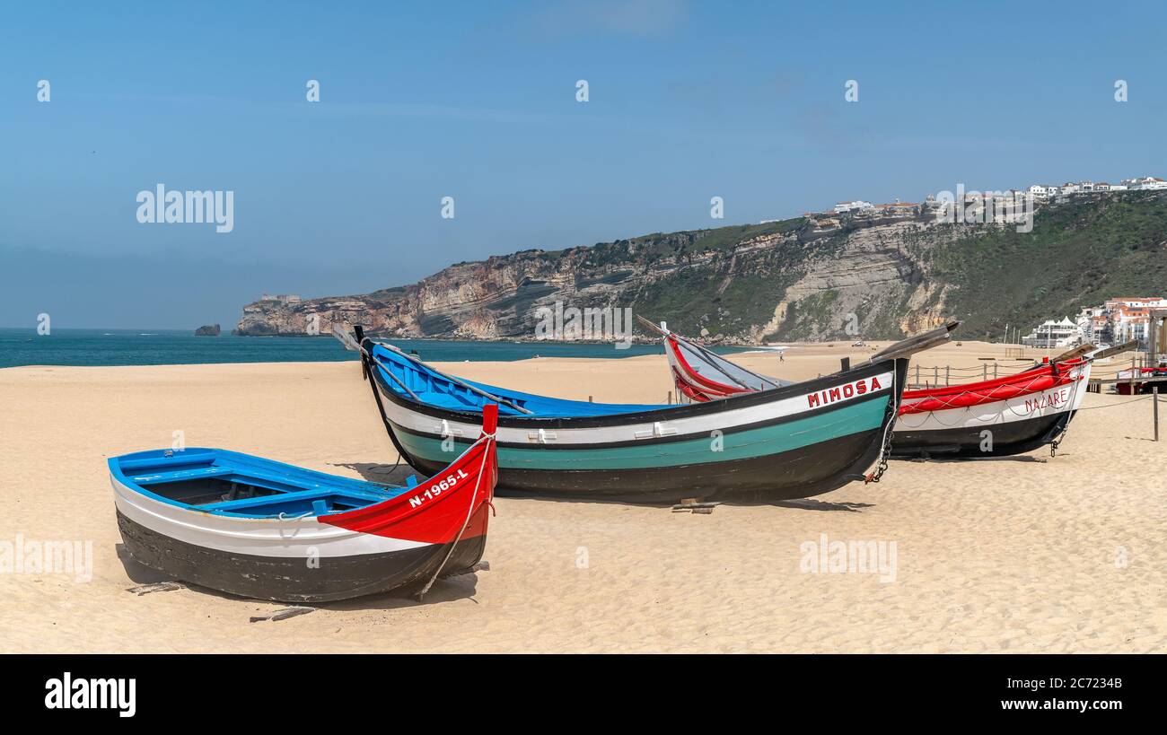 Nazaré, Portugal - avril 2018 : ancien bateau de pêche traditionnel coloré en bois sur la plage du village de pêcheurs de Nazaré.la haute falaise de Nazaré Sitio A. Banque D'Images