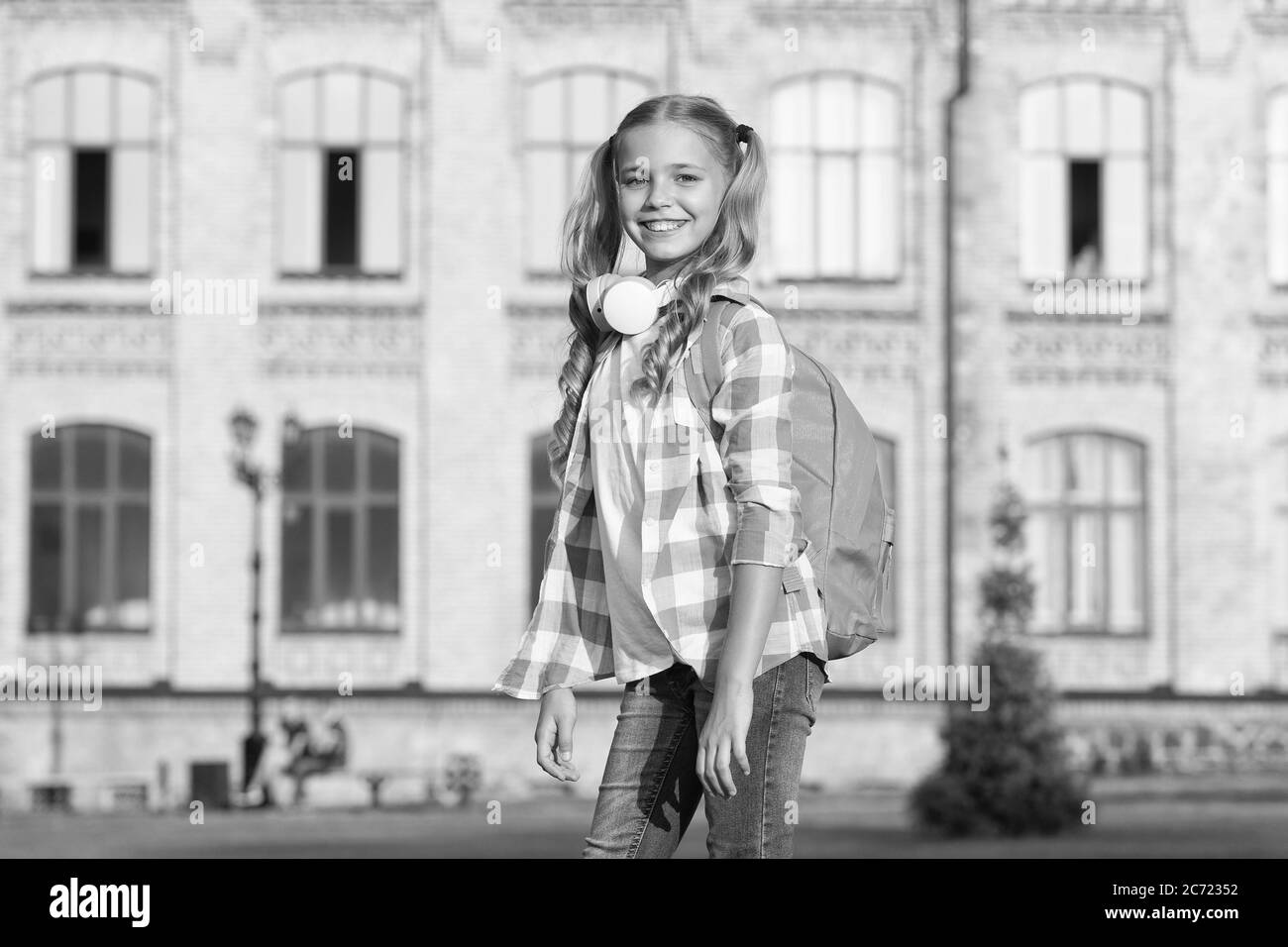 petite fille porte une chemise à carreaux. enfant avec casque au coucher du soleil. enfant printemps et mode d'été. enfance heureuse. e-learning avec ebook. technologie moderne. mélomane et sac à dos. Banque D'Images