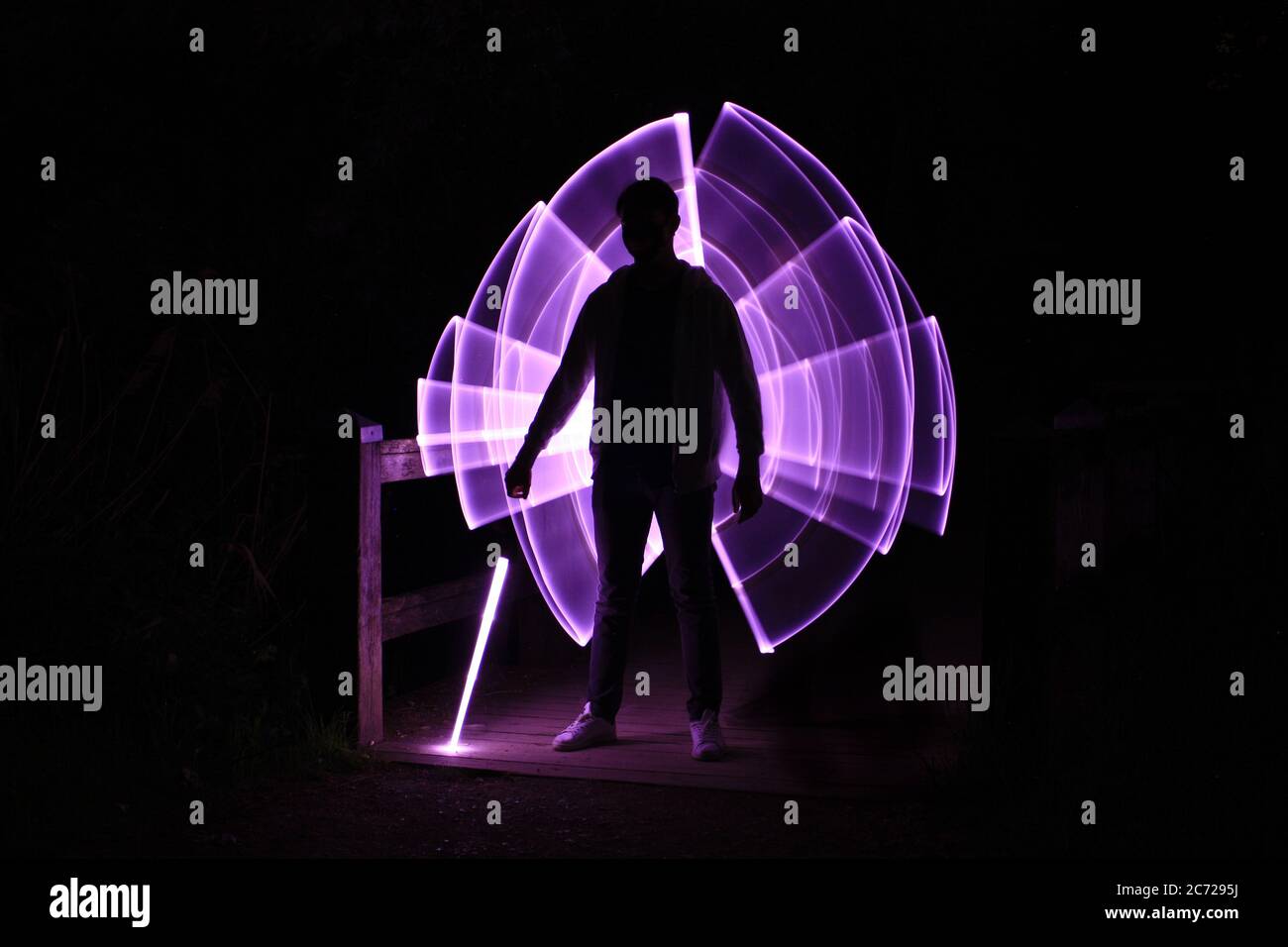 Silhouette d'un homme debout avec un sabre laser avec des dessins au néon et des led à la peinture au néon Banque D'Images