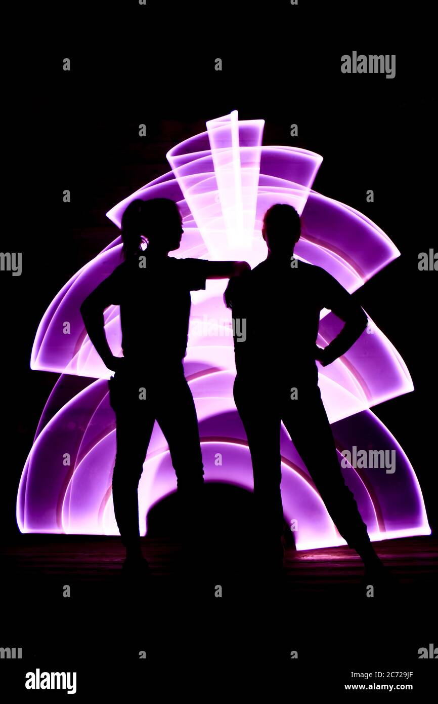 Silhouette de deux femmes devant. Fille penchée sur l'épaule de son ami. Forme courbe abstraite, couleur rose avec un sabre clair en arrière-plan. Banque D'Images