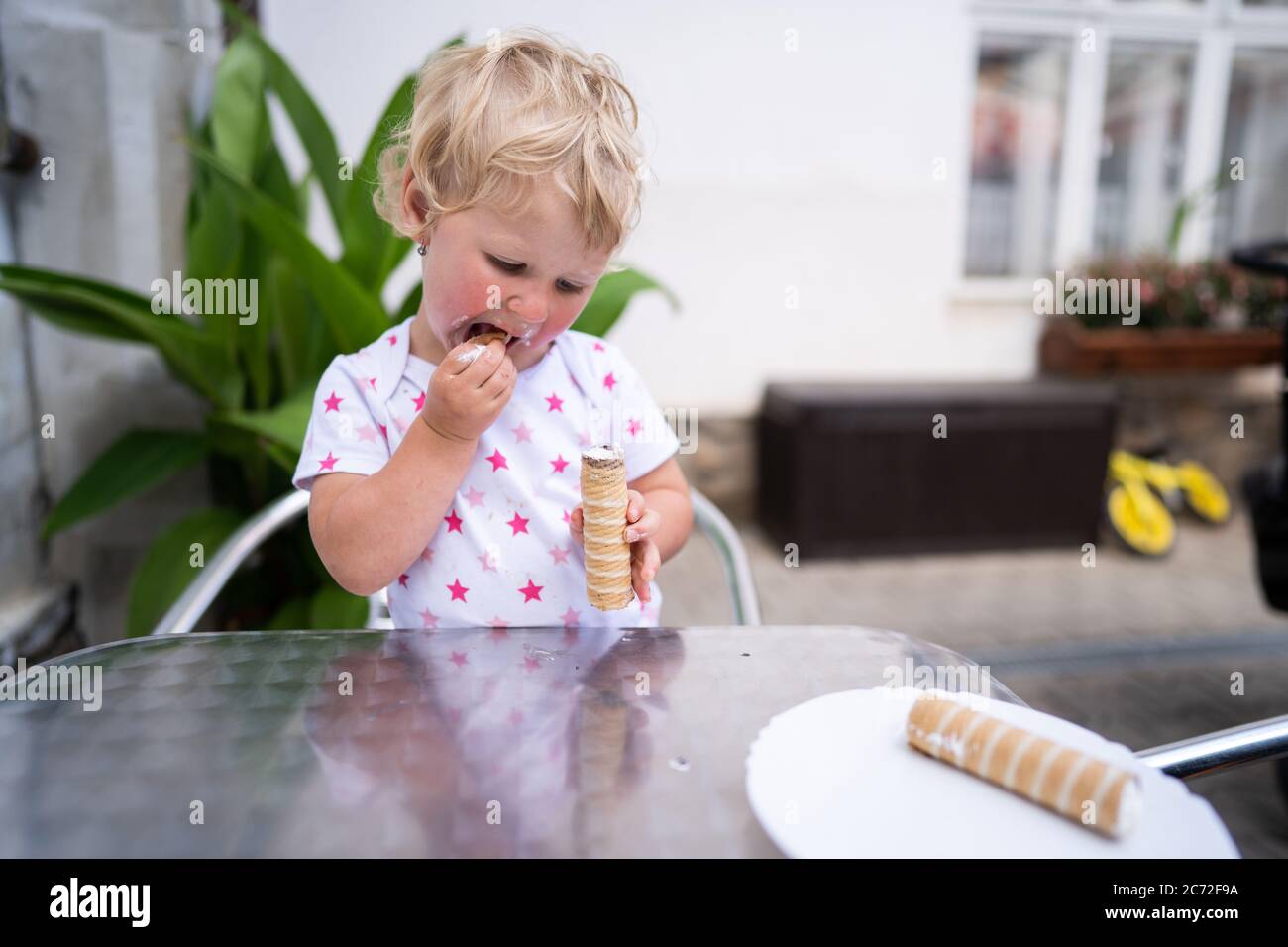 Petite fille mangeant tube avec crème fouettée Banque D'Images