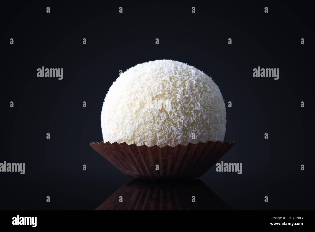 Grande Candy de noix de coco ou boule à gâteau avec garniture au chocolat blanc dans une assiette isolée Banque D'Images