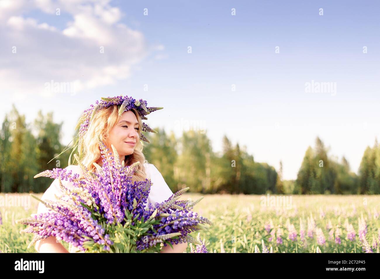 Une belle, heureuse fille appréciant un champ lupin dans un pré, se détendre en plein air, s'amuser, tenant une plante. Le concept de l'harmonie, du bonheur, Banque D'Images