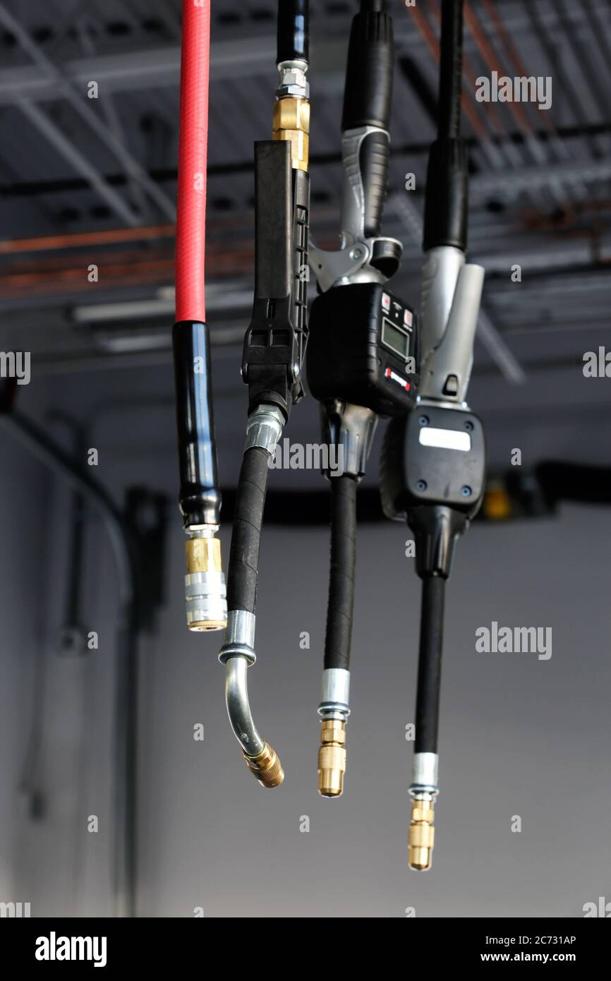 Tuyaux pneumatiques et buses de mesure montés au plafond pour faciliter le changement de l'huile dans une voiture. Banque D'Images