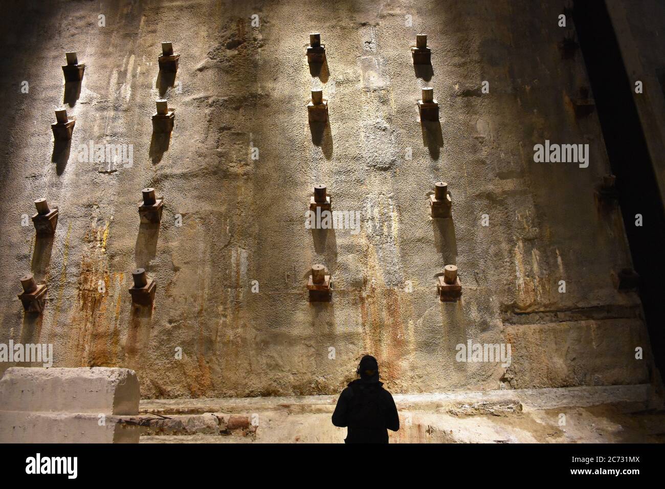 Un visiteur regarde le mur de lisier dans le Foundation Hall du 9/11 Memorial Museum, New York. Le mur présente des taches de rouille et des supports métalliques. Banque D'Images