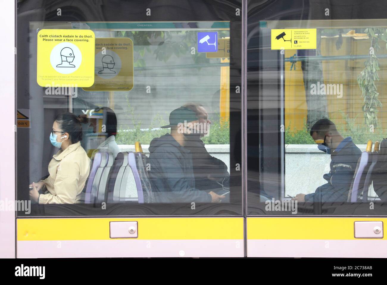 Dublin. 13 juillet 2020. Des personnes portant un masque facial sont vues sur un tramway à Dublin, Irlande, le 13 juillet 2020. Porter un masque ou un masque sur les transports publics irlandais est un must à partir de lundi ou on pourrait faire face à une amende de 2,500 euros (2,837 dollars US) ou une peine d'emprisonnement de six mois, voire les deux, selon les nouvelles réglementations émises par le gouvernement irlandais. Crédit: Xinhua/Alay Live News Banque D'Images