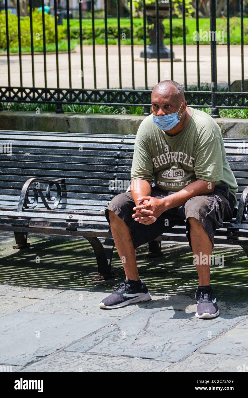 La Nouvelle-Orléans, Louisiane/Etats-Unis - 7/8/2020: Homme portant un masque de visage et assis sur un banc de parc au bord de Jackson Square dans le quartier français Banque D'Images